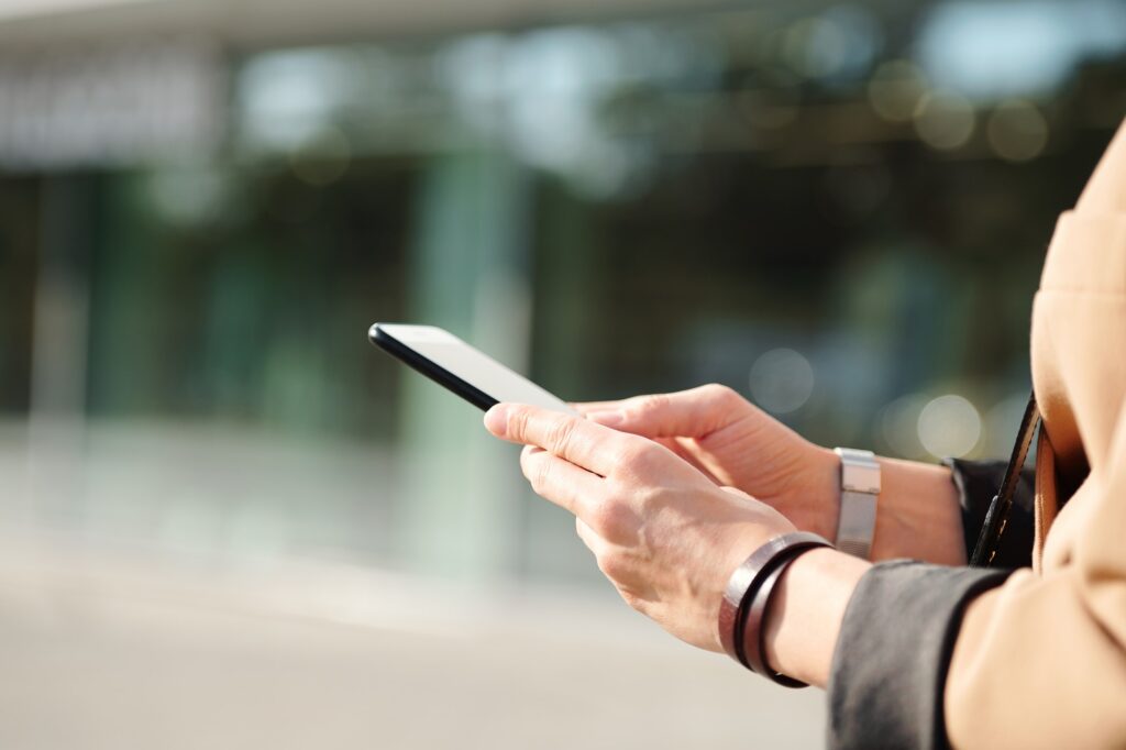 Hands of contemporary businesswoman with smartphone scrolling through contacts