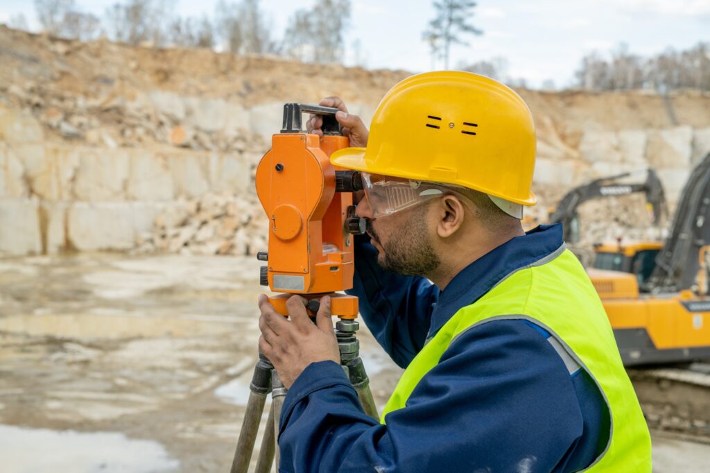 Young surveyor doing engineering work with total station